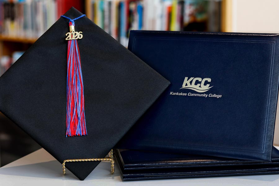 A 2026 graduation cap and tassel next to a Kankakee Community College diploma cover.